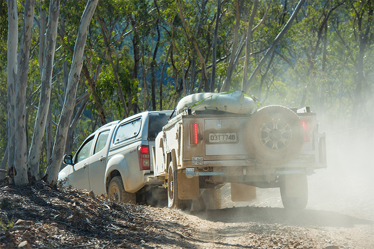 4WD towing a camper trailer through a dusty road