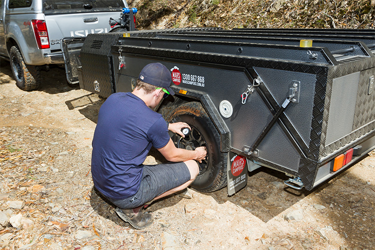 A man changing a camper trailer tyre